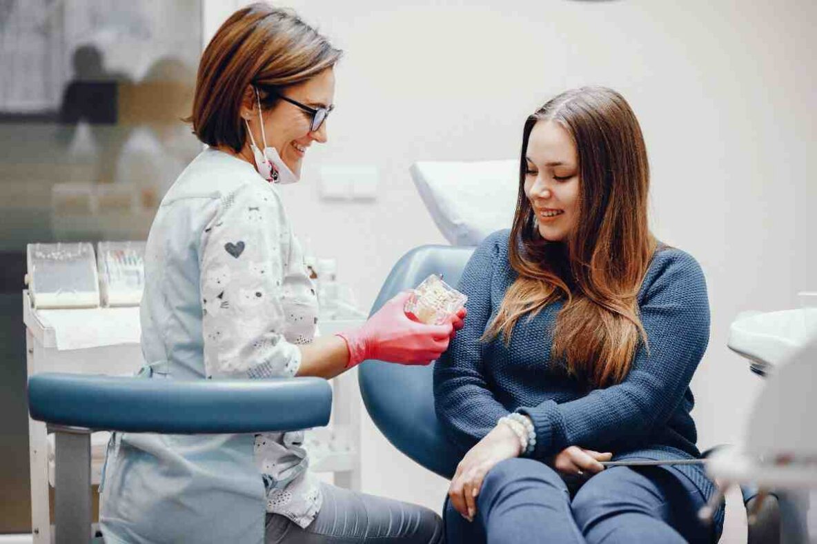 Smiling woman sitting in a dental chair beside orthodontic equipment during a clear aligner consultation.