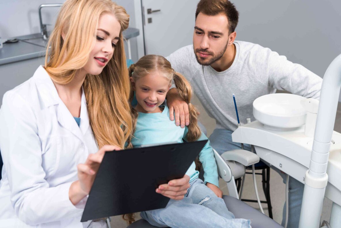 Dentist reviewing a treatment plan with a child patient and parent.